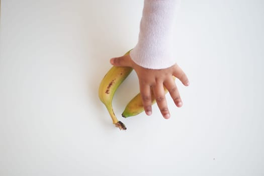 top view of child hand reaching for a banana ,