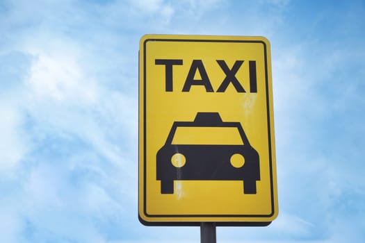 Close-up photo of a yellow Taxi stand sign attached to a metal pole.