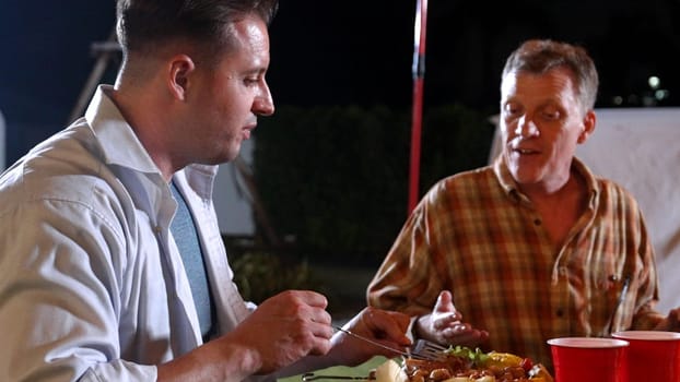 Family gather celebrate holiday. Focus father and grandfather talk about good news and have dinner party food. Outdoor activity for spending time with multigeneration cross generation gap. Divergence.