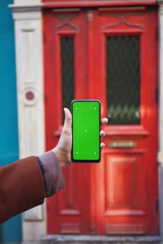 Person holding an smart phone against colorful wood doors. next to a wooden fixture.