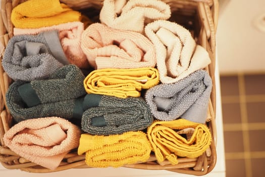 A storage basket made of wood filled with an assortment of towels.