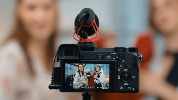 Rear view behide camera screen display two women influencer shoot vlog video review clothes prim social media or blog. Girls with apparel studio lighting for live streaming marketing recording session