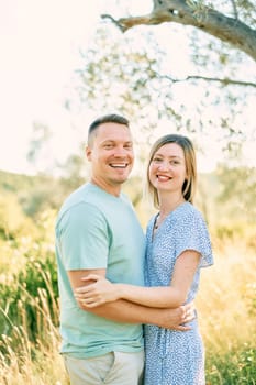 Smiling man and woman hugging while standing in a park. High quality photo