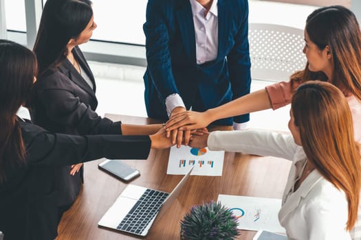 Businesswomen joining hands in group meeting at modern office room showing teamwork, support and unity in work and business. Female power and femininity concept. uds