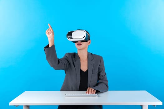 Smart manager wearing VR glasses while sitting at table with keyboard. Businesswoman pointing to manage data analysis while using suit and visual reality headset and enter in metaverse. Contraption.