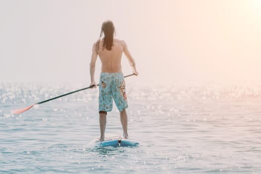 Man Sea Sup. Strong athletic man learns to paddle sup standing on board in open sea ocean on sunny day. Summer holiday vacation and travel concept. Aerial view. Slow motion.