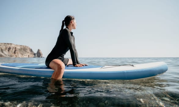 Woman sup yoga. Middle age sporty woman practising yoga pilates on paddle sup surfboard. Female stretching doing workout on sea water. Modern individual hipster outdoor summer sport activity