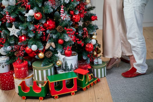 Romantic couple standing near Christmas tree at home and hugging.