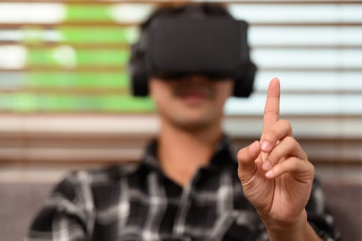 Young man wearing virtual reality headset touching something.