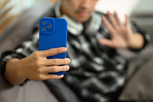 Close up view of male hands using smartphone taking selfie while sitting on couch at home.