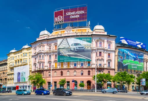 Budapest, Hungary - 1 May 2024: A pink historical building with advertising banners in the intersection of Vaci ut and Terez krt.