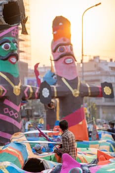 poor labourer looking up at the massive colorful paper effigy of ravan traditionally burnt on the hindu festival of dussehra in India