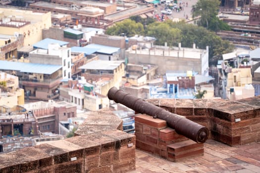 Ancient iron cannon set on the walls of a fort looking out over the city of jodhpur, jaipur, udaipur showing the defences of the ancient Rajput kings