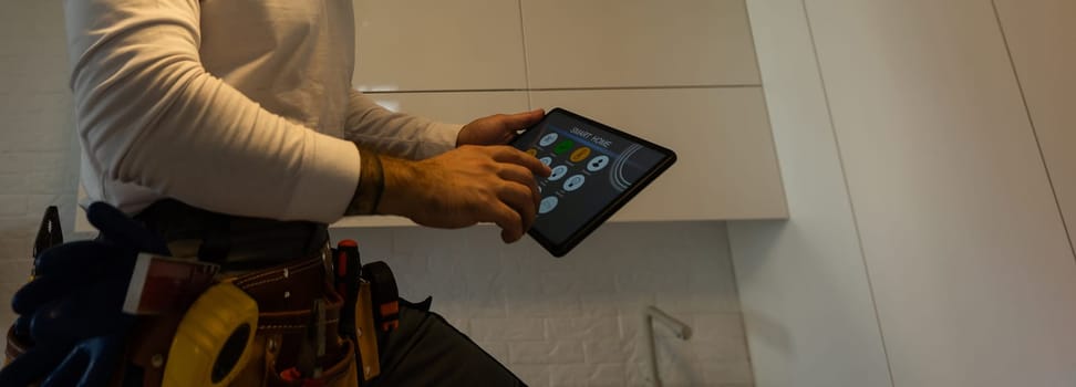 A worker looks at a tablet computer. Master with an electronic tablet in his hands.