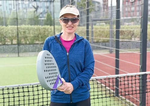 Woman playing padel in a green grass padel court behind the net. High quality photo