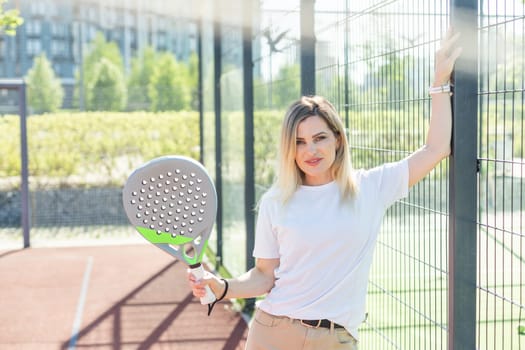 Young sporty woman padel player hitting ball with a racket on a hard court. High quality photo