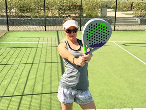 Happy female paddle tennis player during practice on outdoor court. Copy space. High quality photo