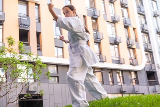 Young active girl wearing in white kimono with white belt performing martial arts kick skills. sporty karate woman improving fight technique on Chinese bridge. concept of sport. High quality photo