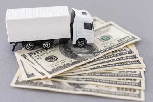 White toy truck lie on dollars, space for text. High quality photo