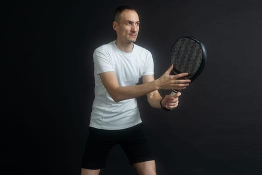 Beautiful man playing paddle tennis, racket in hand concentrated look. Young sporty boy ready for the match. Focused padel athlete ready to receive the ball. Sport, health, youth and leisure concept. High quality photo