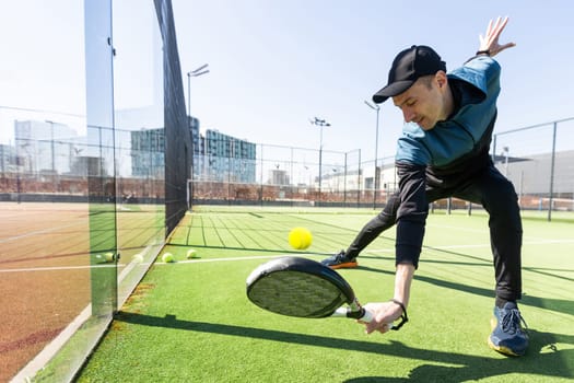 Man playing padel in a green grass padel court indoor behind the net. High quality photo