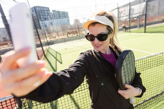 Happy female paddle tennis player during practice on outdoor court looking at camera. Copy space. High quality photo