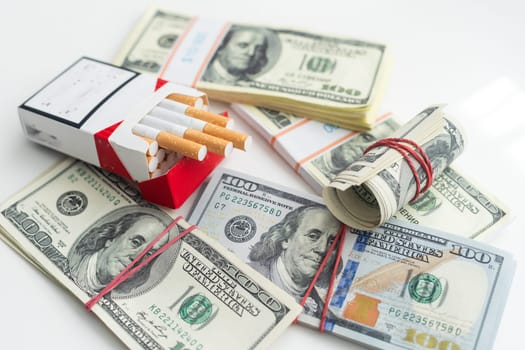 white cigarettes lying on the dollar bills. concept of financial cost of smoking. High quality photo