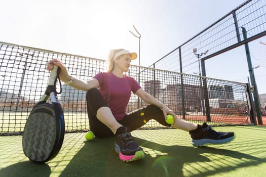 Happy female paddle tennis player during practice on outdoor court looking at camera. Copy space. High quality photo