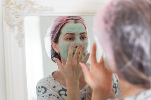 Self care: a woman applying clay mask to her face. High quality photo