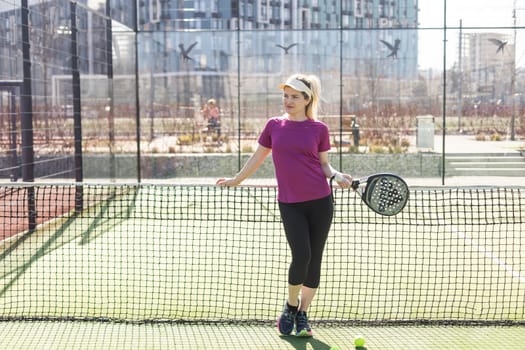 Ukraine Kyiv, March 31 2024. A girl in sportswear is training on a paddle tennis court. Concept of women playing paddle. High quality photo