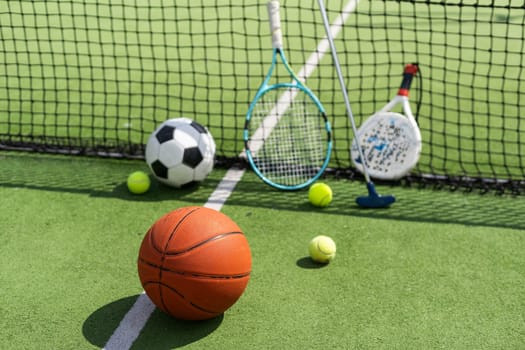 football soccer ball basketball tennis ball and racket laid on grass at sunset. High quality photo