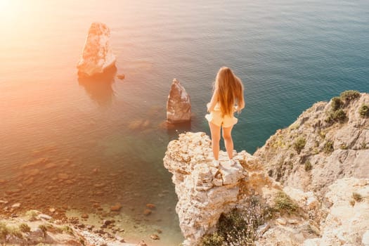 Woman travel sea. Happy tourist taking picture outdoors for memories. Woman traveler looks at the edge of the cliff on the sea bay of mountains, sharing travel adventure journey.