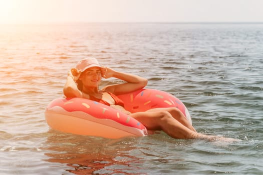 Summer Vacation Woman in hat floats on an inflatable donut mattress, a water toy swim ring. Unrecognizable young woman relaxing and enjoying family summer travel holidays vacation on the sea