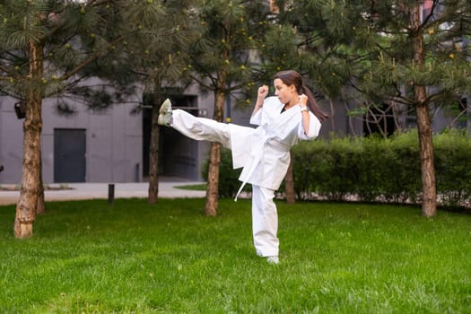 Young active girl wearing in white kimono with white belt performing martial arts kick skills. sporty karate woman improving fight technique on Chinese bridge. concept of sport. High quality photo