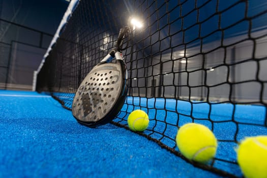 Kyiv, Ukraine, April 18, 2024. Black professional paddle tennis racket and ball with natural lighting on blue background. Horizontal sport theme poster, greeting cards, headers, website and app. High quality photo