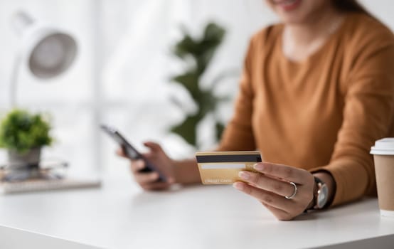 Happy young woman is shopping online and paying with credit card using online banking application..