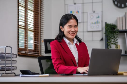 Senior accountant working on financial and marketing summary on laptop in office.