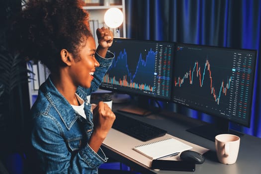 African woman blogger exited with happy face, pointing on screen with valued stock market achievement at high profit. Concept of exchange investment online in trading application on pc. Tastemaker.