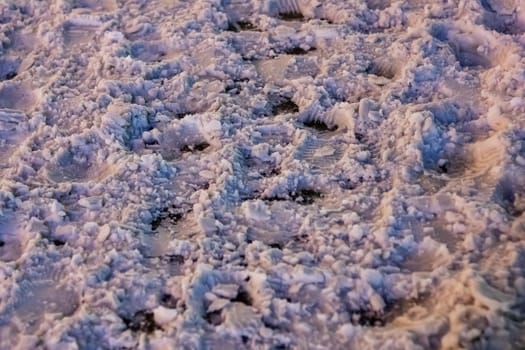 A close up of a pile of freezing snow on the ground, contrasting with the green grass nearby, creating a beautiful natural landscape