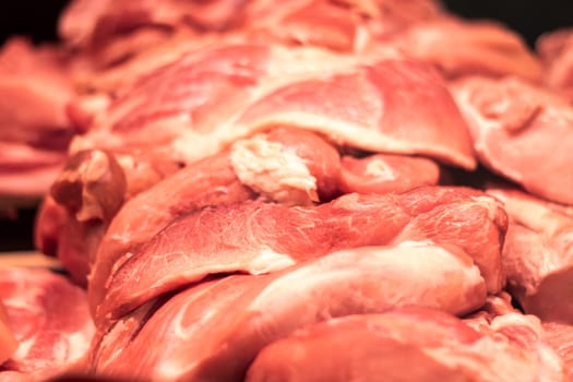 A heap of animal product, either pork or beef, is resting on a tabletop. This raw meat can be used as an ingredient for various dishes in different cuisines