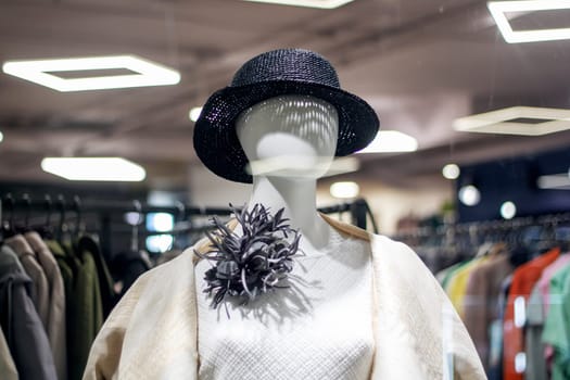 A stylish mannequin showcasing a hat and jacket in a boutiques display case, highlighting the fusion of fashion design and art in retail