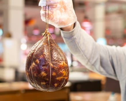 Man's hand holding a Matsik. Jerky pork meat placed in the pork stomach and dried for several months. Traditional Ukrainian appetizer. High quality photo