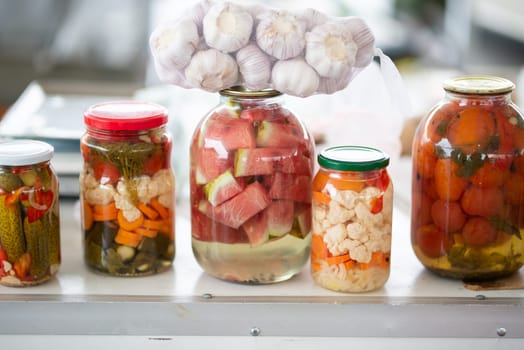 glass jars of fermented cabbage, cauliflower, cucumbers, onions, carrots, vegetables on a light background. fermentation is a source of probiotics. High quality photo