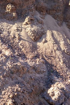 A mixture of soil, brown bedrock, and small rocks resembling a mini landscape. The pattern of rocks creates an interesting contrast in the grassy area, similar to a road surface with asphalt