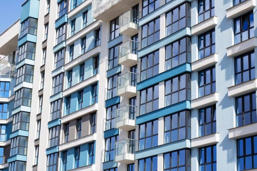 A modern urban design building with a striking facade featuring numerous windows and balconies, offering stunning views of the blue sky. It may be a condominium, commercial building, or tower block