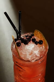 Closeup of vibrant refreshing tropical Zombie cocktail with rum, grapefruit juice and spicy cinnamon syrup, served chilled with crushed ice garnished with dehydrated citrus and currant berries
