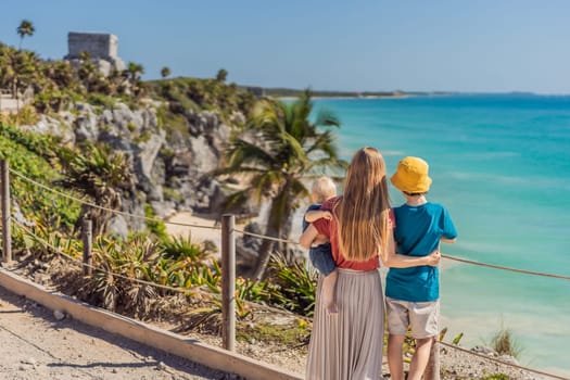 Mother and two sons tourists enjoying the view Pre-Columbian Mayan walled city of Tulum, Quintana Roo, Mexico, North America, Tulum, Mexico. El Castillo - castle the Mayan city of Tulum main temple.