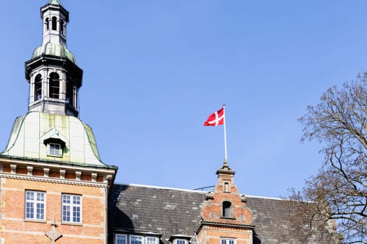Danish flag on the roof of a building against a blue sky. High quality photo