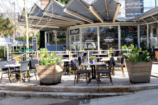 Cozy street cafe with empty tables on a sunny day in Copenhagen, Denmark - April 21