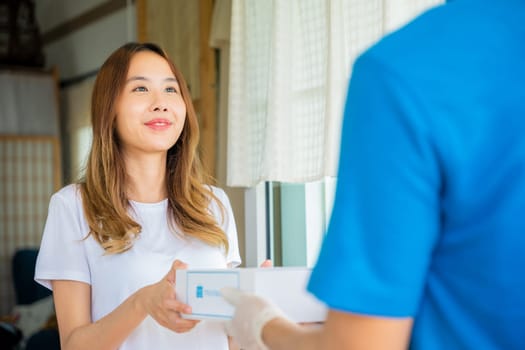 Sick Asian young woman receive medicine first aid pharmacy box from hospital delivery service, happy female receiving patient medicine drug from delivery man, healthcare medicine online concept